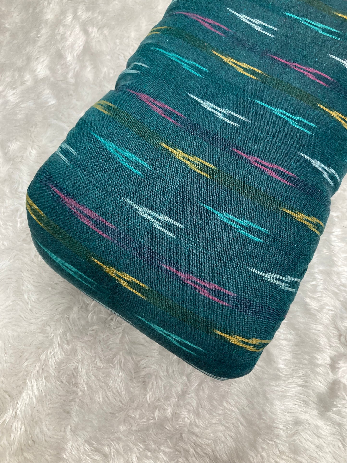 Teal fabric with colorful abstract pattern on a white textured background