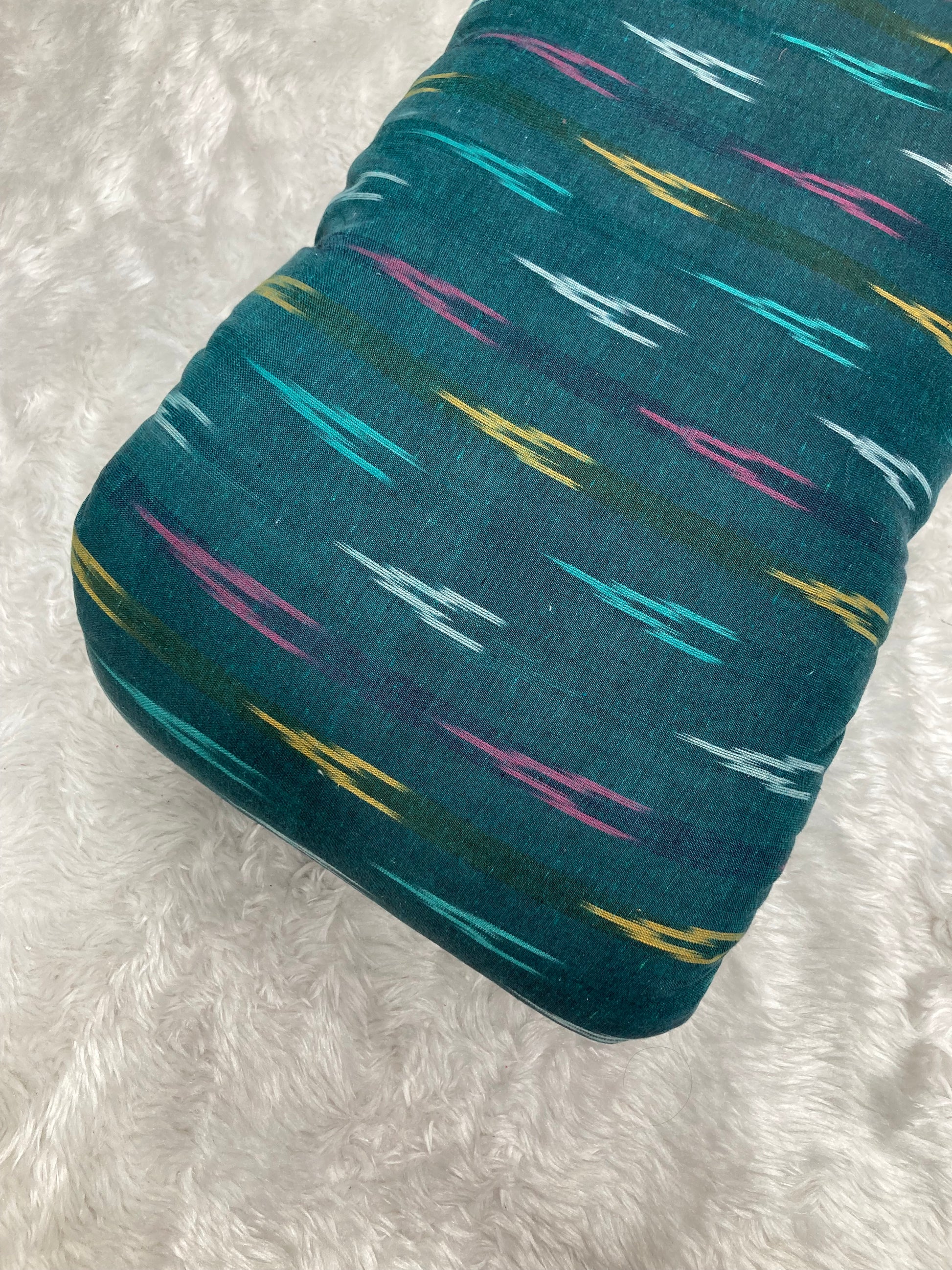 Teal fabric with colorful abstract pattern on a white textured background
