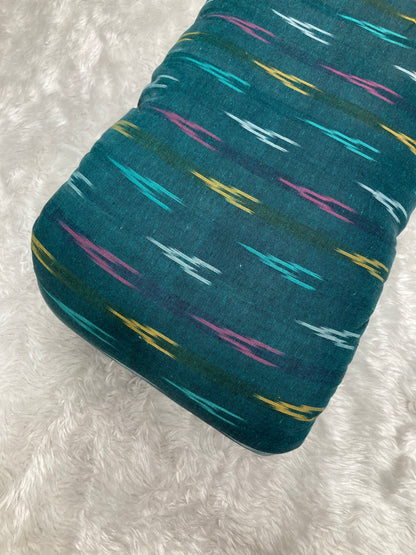 Teal fabric with colorful abstract pattern on a white textured background