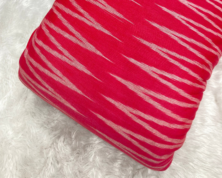 Red pillow with white stripes on a white fluffy surface