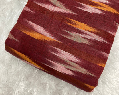 Fabric with a pattern of red, orange, and white on a textured white background