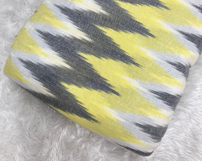 Roll of fabric with yellow and gray pattern on a textured white surface