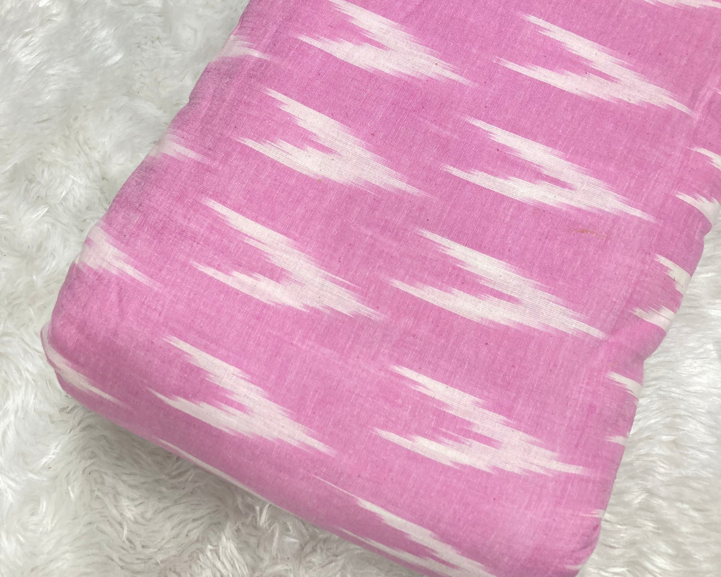 pink fabric with white pattern on a white fluffy background