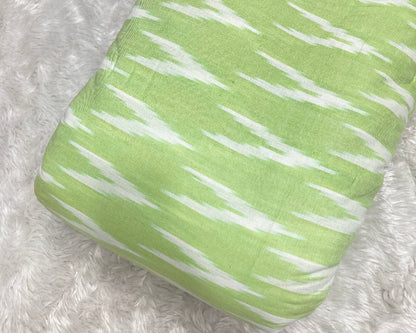 Green fabric with white patterns on a textured gray background